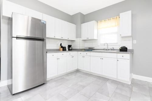 a kitchen with white cabinets and a stainless steel refrigerator at The Texas Hold-em Duplex- 3BR Free Parking, Minutes From Falls & Casino in Niagara Falls