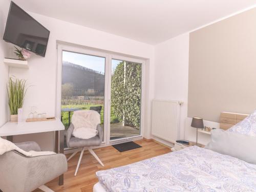 a bedroom with a bed and a chair and a window at Ferienweingut Lütz in Pünderich