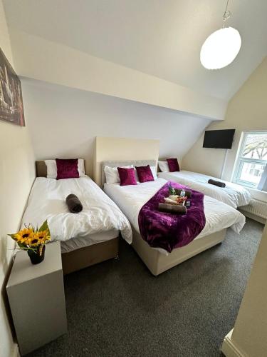 two beds in a room with purple pillows at Elm Vale Lodge in Liverpool