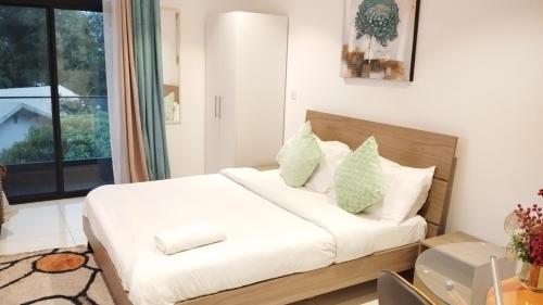 een slaapkamer met een bed met witte lakens en groene kussens bij Golden Place Properties At The Embassy Gardens in Accra