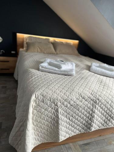 a white bed with two towels on top of it at APARTAMENTY CENTRUM in Kostrzyn nad Odrą