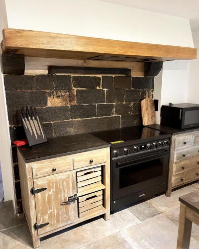 a kitchen with a black oven and a brick wall at Gite Mameye in Tellin