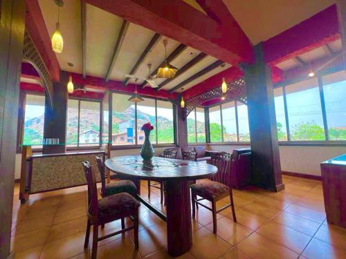 a dining room with a table and chairs and windows at Mount View Villa in Lonavala
