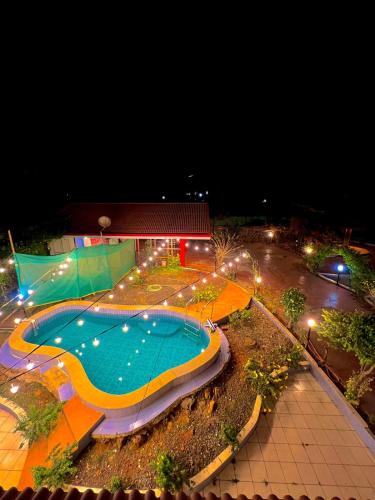 a large swimming pool at night with lights at Mount View Villa - The Dream Stays ll Pvt Pool ll Garden ll 3Ac rooms in Lonavala