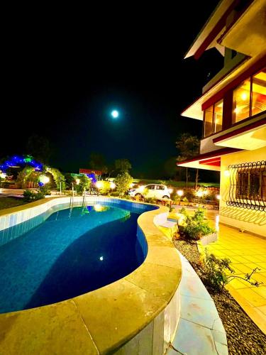 a swimming pool in front of a building at night at Mount View Villa - The Dream Stays ll Pvt Pool ll Garden ll 3Ac rooms in Lonavala
