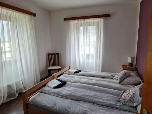 a bedroom with two beds and a chair and windows at Ristorante Notari cà di gust vecc in Malvaglia