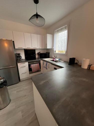 une cuisine avec des armoires blanches et un réfrigérateur en acier inoxydable dans l'établissement Appartement Brise Marine, à Grandcamp-Maisy