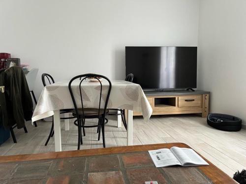 a table with chairs and a television in a living room at Appartement Brise Marine in Grandcamp-Maisy