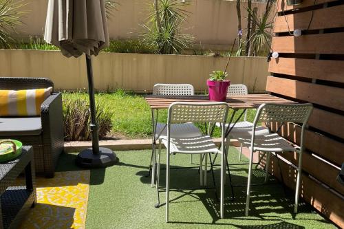 une table avec des chaises et un parasol sur une terrasse dans l'établissement Charming refurbished cocoon with swimming pool, à Cannes
