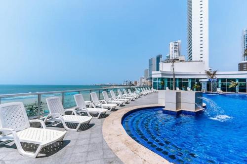 una fila de sillas blancas junto a una piscina en Apartamento con vista al mar piso 19 Bocagrande, en Cartagena de Indias