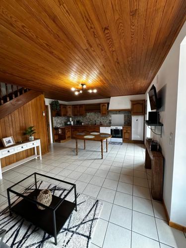 una grande cucina con soffitto in legno e tavolo di L’Hacienda, maison de caractère a Saint-Martin-de-Valamas
