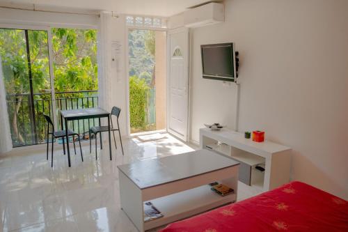 un salon avec un bureau et une table avec des chaises dans l'établissement La Turbie, charmant logement., à La Turbie