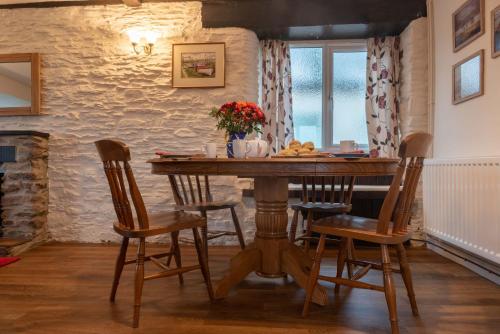 Dunkery Cottage Wheddon Cross في مينهيد: غرفة طعام مع طاولة وكراسي