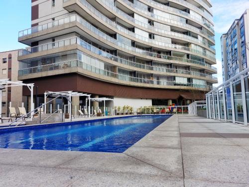 a building with a swimming pool in front of a building at Book Santos - Condomínio Unlimited - Apartamento com Vista Mar e Apartamento com Vista Piscina in Santos