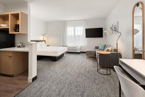 ロンバードにあるTownePlace Suites Chicago Lombardのベッドとリビングルームが備わるホテルルームです。