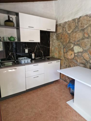 a kitchen with white cabinets and a stone wall at Villa Lara in Molunat