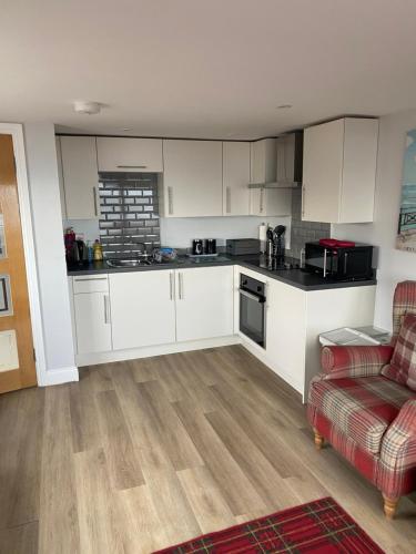 a kitchen with white cabinets and a red couch at Beach Cottage in Berwick-Upon-Tweed
