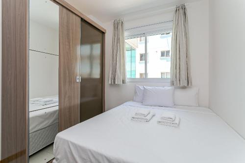 um quarto com uma cama branca e uma janela em Piscina com Vista MAR próximo à UFSC #PANTA03 em Florianópolis