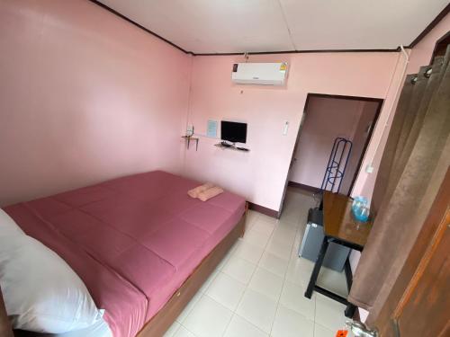 a small room with a pink bed and a desk at โพธิ์ทองริมทุ่ง Pothong Rimtung Hotel in Fang