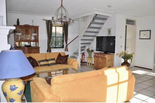 a living room with yellow couches and a tv at Buitenplaats 144 in Callantsoog