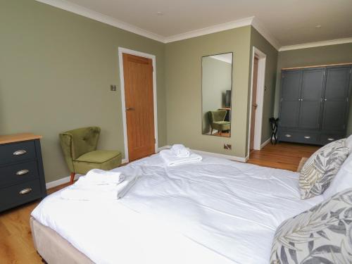 a bedroom with a large white bed and a chair at Sea View in Carmarthen