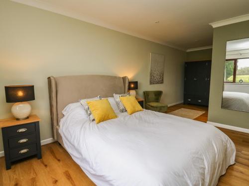 a bedroom with a bed with white sheets and yellow pillows at The Oaks in Carmarthen
