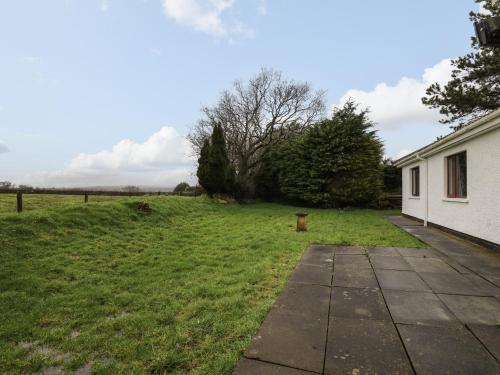 a grassy yard next to a white house at The Oaks in Carmarthen