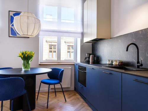 a kitchen with blue cabinets and a table with chairs at Tyzenhauz Apartments Siemiradzkiego Street in Krakow