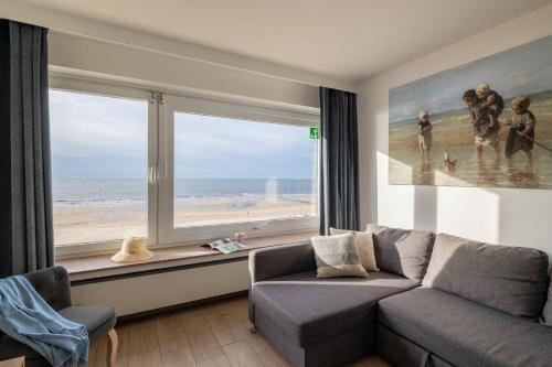 een woonkamer met een bank en een groot raam bij Cosy studio with Amazing Seaview T67 in Oostende