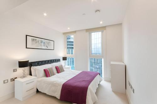 um quarto branco com uma cama grande e janelas em Still Life Aldgate Deluxe em Londres