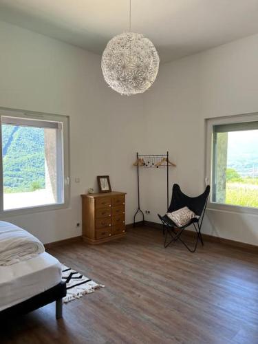 Schlafzimmer mit einem Bett, einem Stuhl und Fenstern in der Unterkunft Maisonnette des vignes in Albertville
