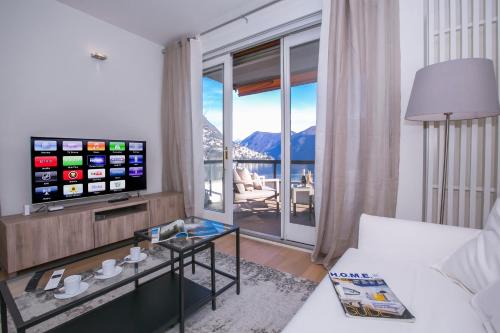 ein Wohnzimmer mit einem Sofa, einem TV und einem Tisch in der Unterkunft Lugano Motta - Happy Rentals in Lugano