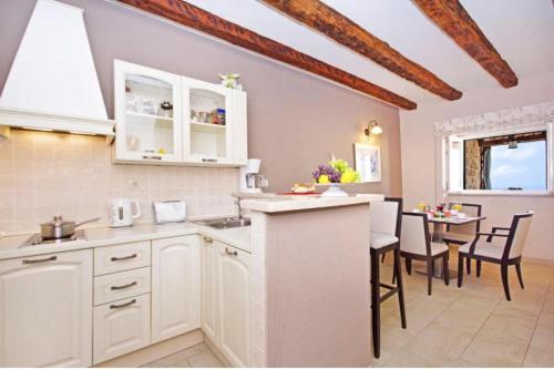 a kitchen with white cabinets and a dining table at Luxury Panorama Villa Dia in Brsečine