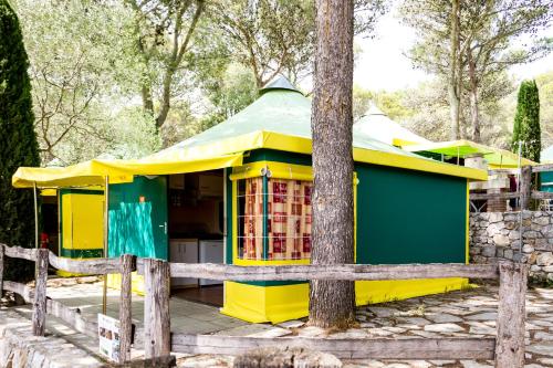 um edifício amarelo e verde com uma árvore em Càmping Castell Montgrí **** em L'Estartit