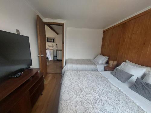 プエルト・アイセンにあるMi Cabañaのベッド2台、薄型テレビが備わるホテルルームです。