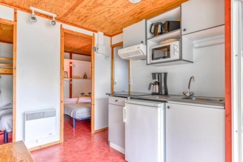 uma cozinha com armários brancos e um lavatório num quarto em Camping LA SERRE em Aigues-Vives