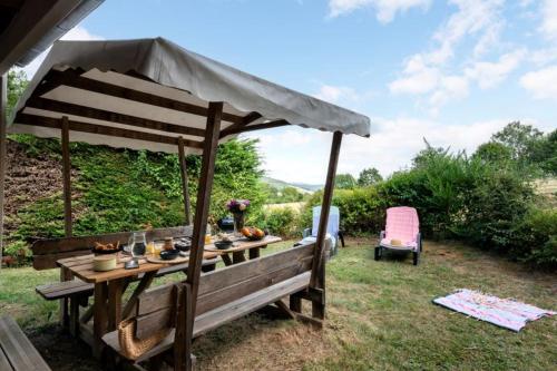a picnic table under a canopy in a garden at Camping LA SERRE in Aigues-Vives