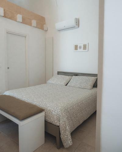 a white bedroom with a bed and a bench at C'era una Volta Apartments in Bisceglie
