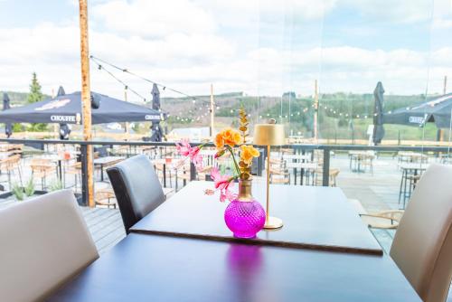 a table with a pink vase with flowers on it at Achouffe Valley in Achouffe