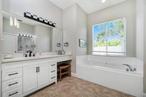 La salle de bains blanche est pourvue d'une baignoire et d'un lavabo. dans l'établissement Newly Remodeled 4BR/3BA, Private Pool, Sleeps 8, à Port Charlotte