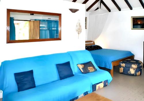een woonkamer met blauwe banken en een spiegel bij Studio a Sainte Anne a 350 m de la plage avec piscine partagee jardin clos et wifi in Sainte-Anne