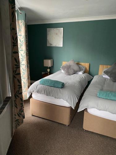 two beds in a room with green walls at The Granary Bar & Grill in Long Sutton