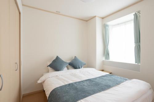 1 dormitorio con cama blanca y almohadas azules en Kagurazaka City House - 神楽坂シティハウス en Tokio