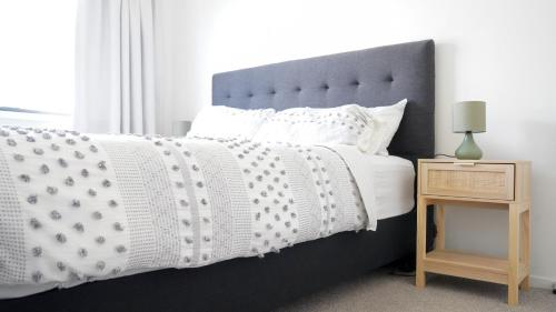a bedroom with a black and white bed and a night stand at Hamilton Hospital Retreat - 2 Bedroom Townhouse Modern Warm Quiet in Hamilton