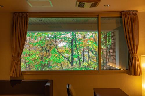 a window with a view of a forest at Morinoyu Hotel Hanakagura in Asahikawa