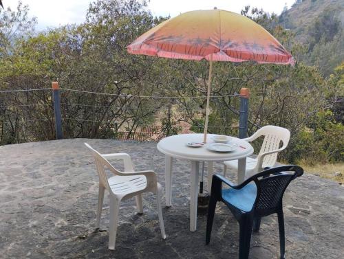 a table with two chairs and an umbrella at Cabaña los cerezos in Ubaté