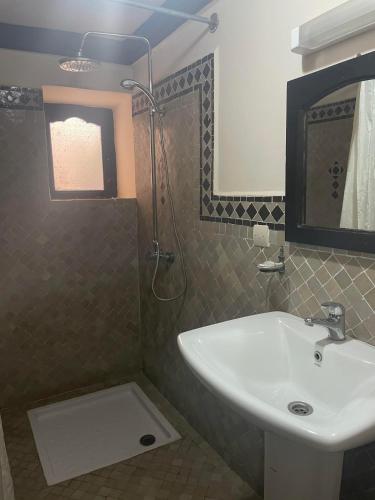 a bathroom with a sink and a shower with a mirror at Riad Al Madina in Essaouira