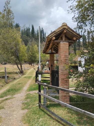 a wooden fence with a brick building next to a gate at Cabaña los cerezos in Ubaté