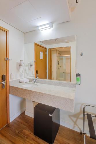 a bathroom with a sink and a large mirror at Transamerica Fit Campinas in Campinas