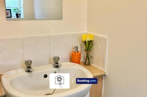 baño con lavabo y jarrón de flores amarillas en Eastleigh House By Your Stay Solutions Short Lets & Serviced Accommodation Southampton With Free Wi-Fi & Close to Airport en Southampton